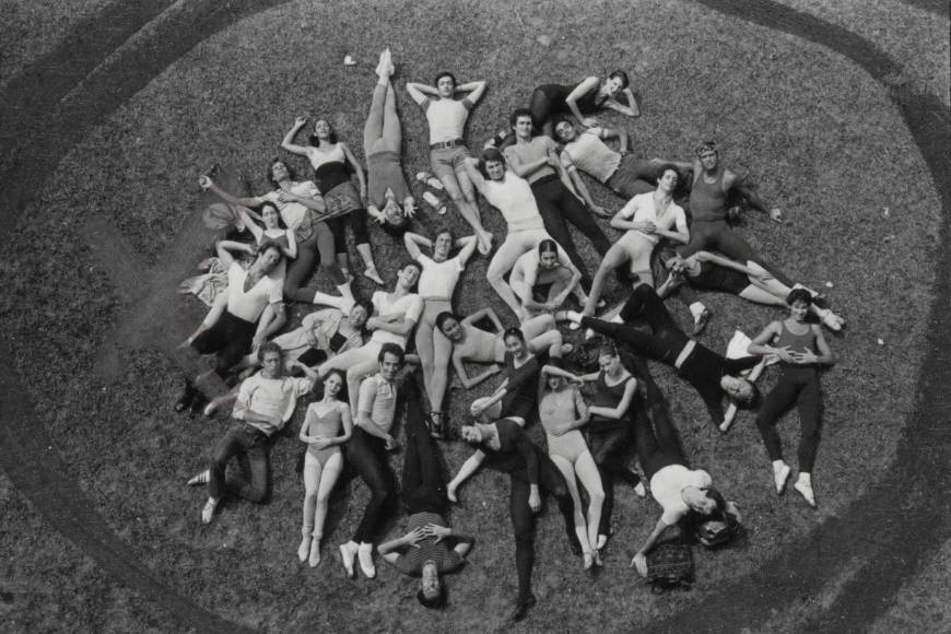 A group of Joffrey dancers lying on the ground in a circle looking up. Point of view is above the dancers looking down.