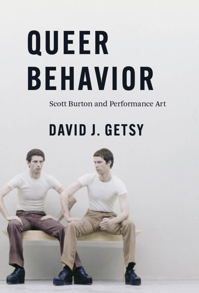 book cover: Two men dressed in a white t-shirt, different colored chinos and platform shoes sitting side by side on what looks like a floating bench. Each has an arm and a leg crossing the other person.